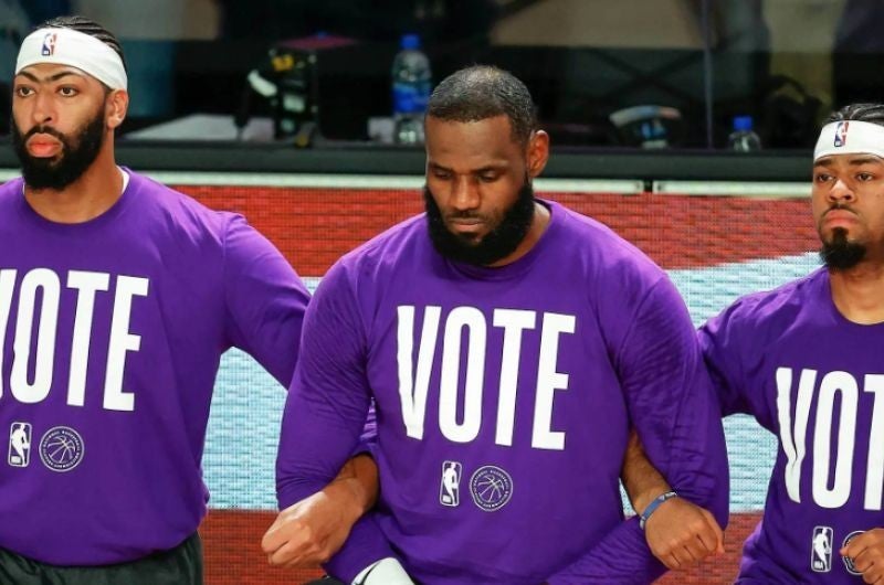photo of Anthony Davis, Lebron James and Quinn Cook of the Los Angeles Lakers wearing NBA vote t-shirts