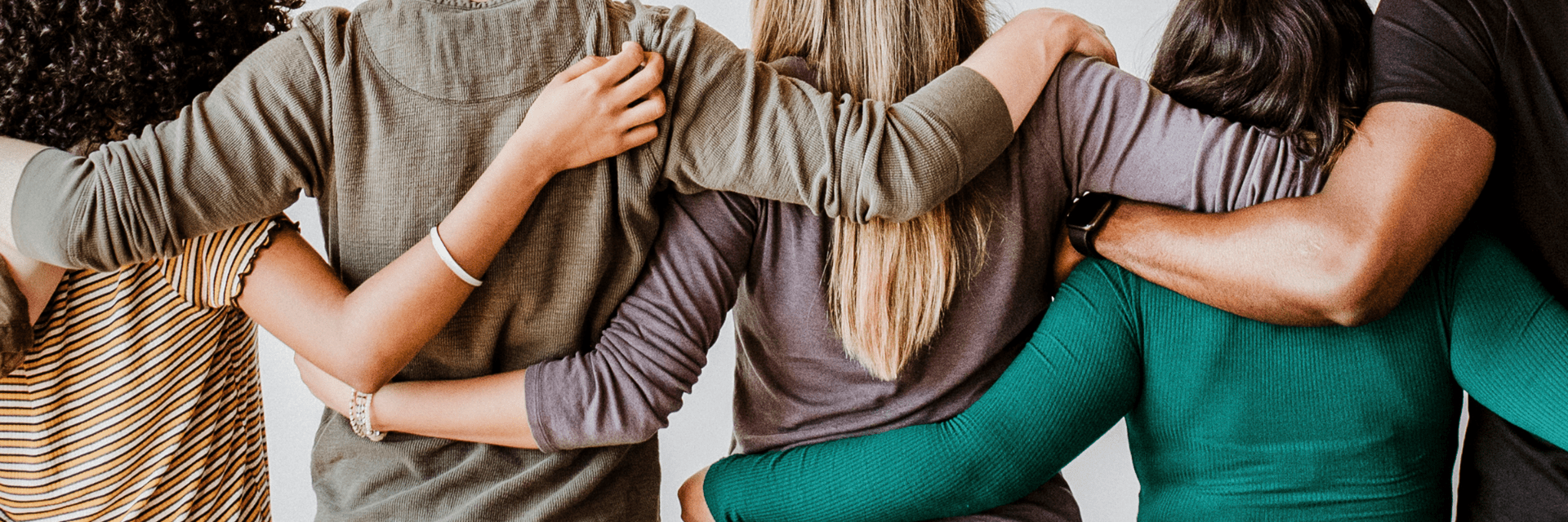 Photo of people with their back to camera with arms around each others backs